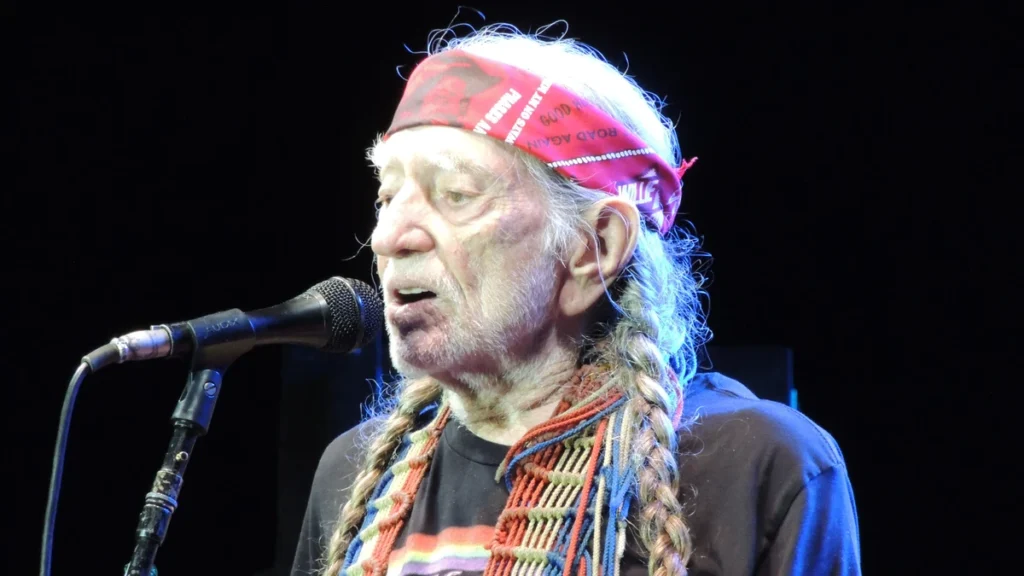 Willie Nelson at the microphone in a red bandana